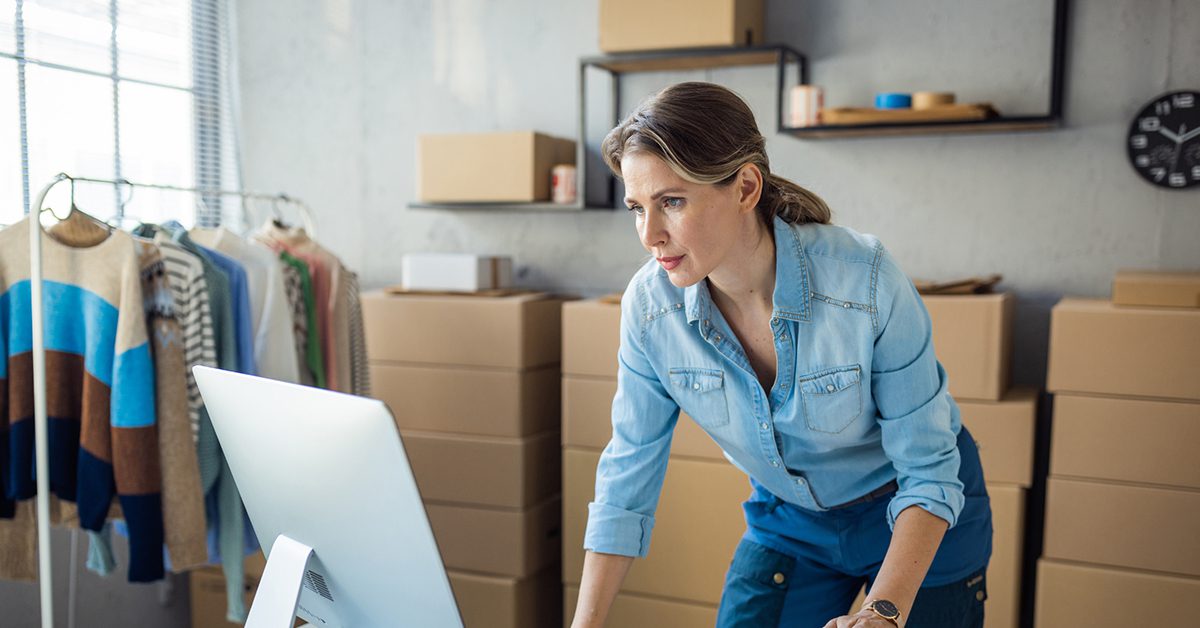 a woman standing at a desk and looking at a computer