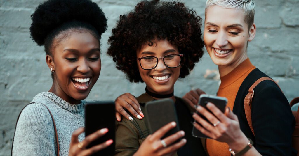 three women interacting with their phones